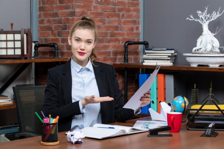 top-view-young-lady-sitting-table-holding-showing-document-office